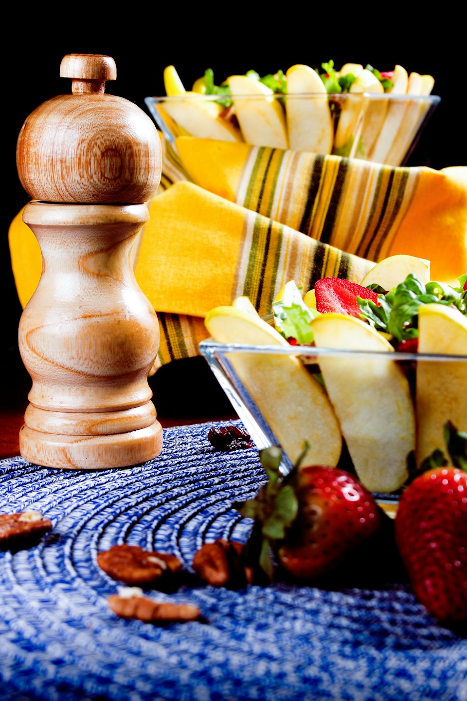 Ciotole di insalata fresca e frutta con macinapepe in legno.